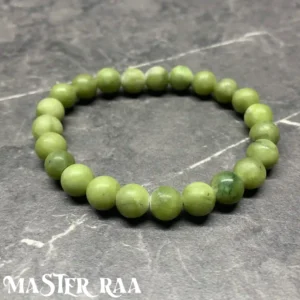 Green Jade crystal bracelet with polished vibrant green beads, laid flat on grey background